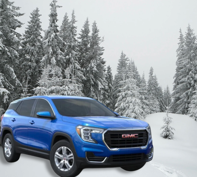 A blue GMC Terrain SUV parked in a snowy forest, highlighting winter readiness.